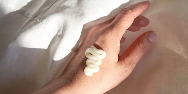 Cream applied to a hand lying on a white sheet