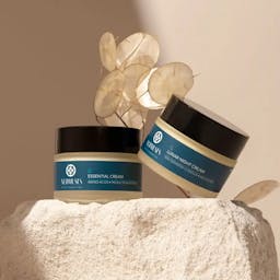 Nudmuses Lunar and Essential Creams next to each other on the rock with Lunaria background