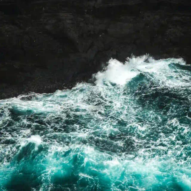 A beach with black sand and blue water