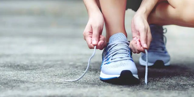 A woman is lacing her lilac running shoes