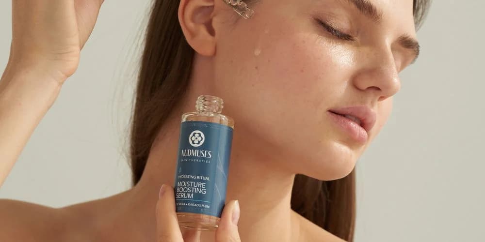 Modelka nakładająca na policzek serum nawaliżające Nudmuses Hydrating Ritual, Moisture Boosting Serum