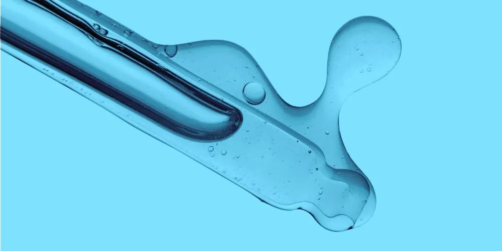 Transparent pipette filled with serum on a blue background