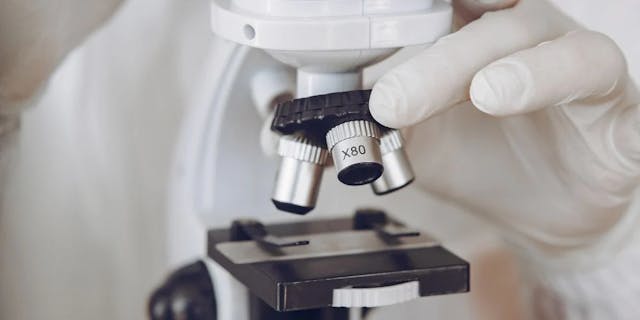 A gloved hand setting up a microscope